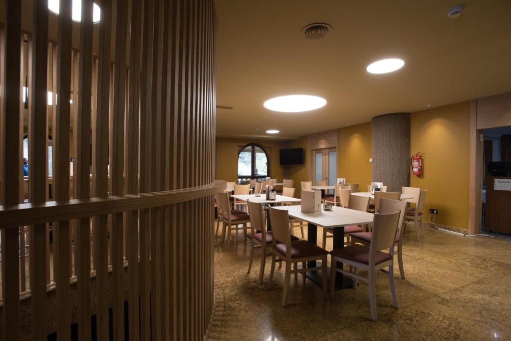Un comedor con mesas y sillas, un separador de madera y un extintor en la pared.