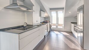 Eine moderne Küche mit Kochinsel, Edelstahlgeräten und einem großen Fenster für natürliches Licht.