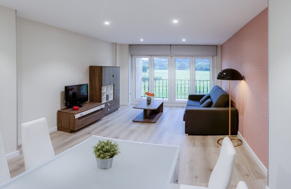 Una sala de estar moderna con televisor, sofá y zona de comedor.