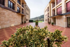 Un patio con un sendero central bordeado por edificios con balcones y plantas en macetas.