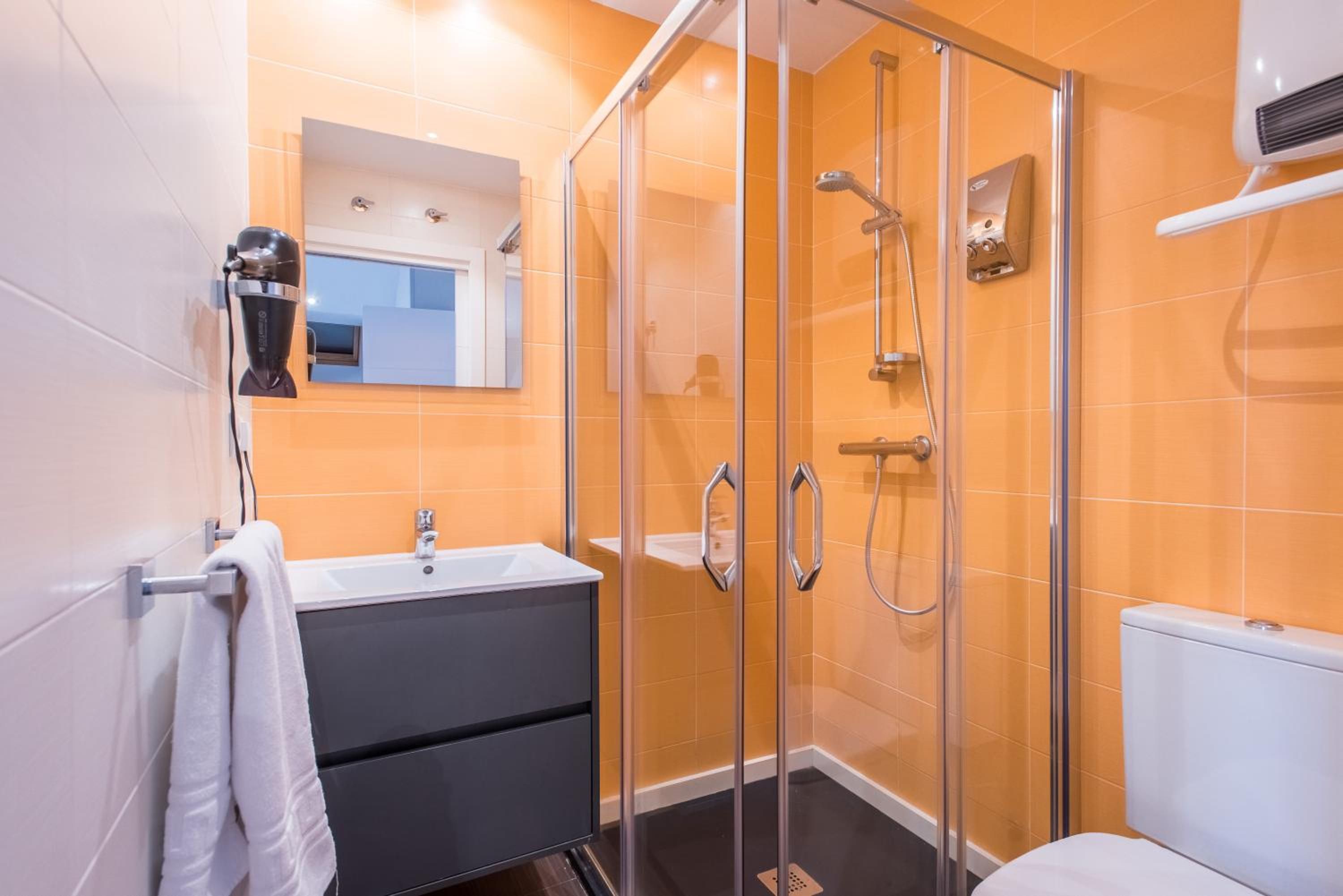 A modern bathroom with a glass shower enclosure, a sink with a mirror, and a toilet.
