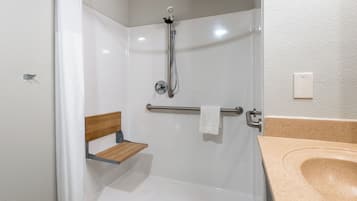 Une douche équipée d’un pommeau de douche à main, d’un porte-serviettes et d’une étagère en bois.