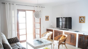 A living room with a sofa, a coffee table, wicker chairs, a TV, and a cabinet. - Villa Casa Blanca (Costa Adeje)