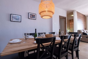 A dining area with a wooden table, black chairs, and a woven pendant light. There are framed pictures on the wall and a door leading to another room. - Villa Casa Blanca (Costa Adeje)