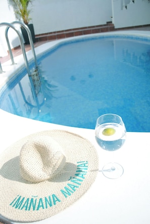 A pool with a metal ladder, a straw hat with "IMANANA" embroidered, and a glass with a lemon slice. - Villa Casa Blanca (Costa Adeje)