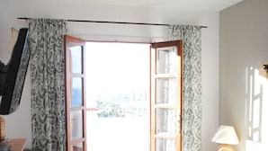 A bedroom with a bed, a chair, a desk, a lamp, and an open door leading to a balcony. - Villa Casa Blanca (Costa Adeje)