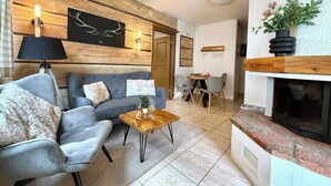 Un salon comprenant un canapé, des fauteuils, une table basse, une cheminée et un coin repas.