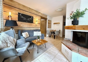 A living room with a sofa, armchairs, a coffee table, a fireplace, and a dining area.