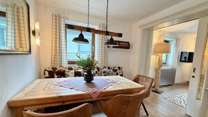 A dining area with a wooden table, four chairs, a vase with a plant, and a checkered table runner. - Belle Kitz 2 by Belle-Stay (Kitzbühel)