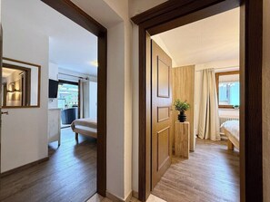 Une chambre dâhĂŽtel avec un plancher en bois, un lit, une table de chevet avec une plante et une fenĂȘtre avec des rideaux.