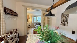 A cozy living room with a wooden coffee table, a cow print sofa, and a dining area with a table and chairs. - Belle Kitz 2 by Belle-Stay (Kitzbühel)