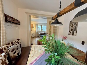 Een gezellige woonkamer met een houten salontafel, een bank met koeienprint en een eethoek met een tafel en stoelen.