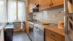 A kitchen with wooden cabinets, a stove, a dishwasher, and a refrigerator. - Casa Alverà (Cortina d´Ampezzo)