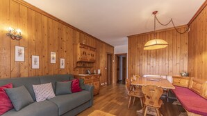 Une pièce chaleureuse avec un plancher en bois, un canapé, une table à manger et un banc.