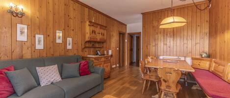 A cozy room with a wooden floor, a sofa, a dining table, and a bench.