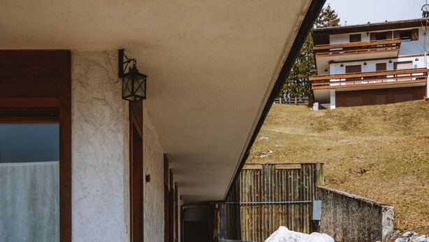 Une entrée dallée de pierres, avec un banc en bois et une table en bois rustique.