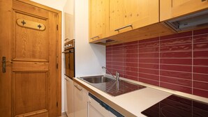 Une cuisine avec des meubles en bois, un évier en acier inoxydable et un dosseret de crédence en carreaux rouges.