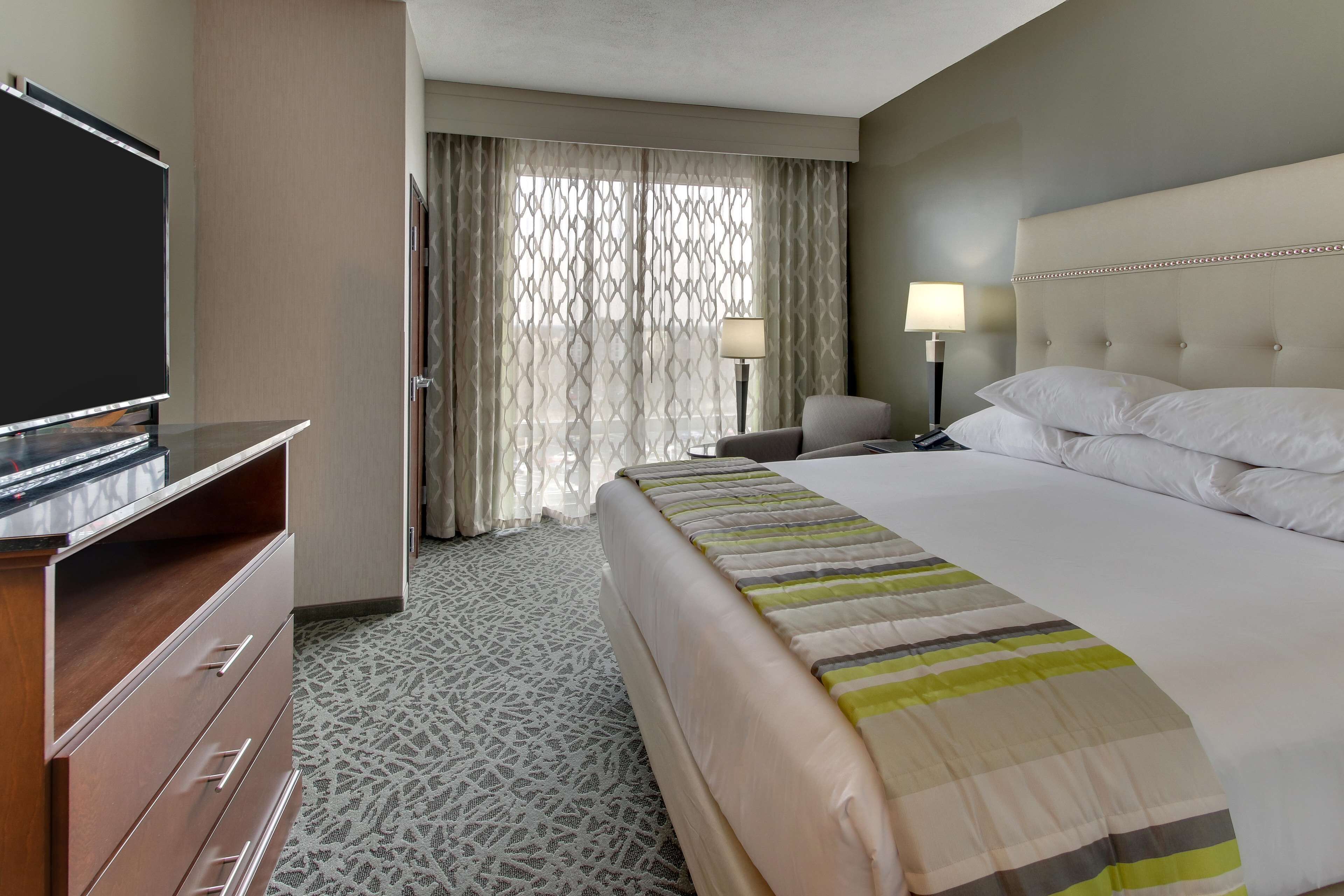 Une chambre d’hôtel avec un grand lit, une télévision, un bureau et une chaise.