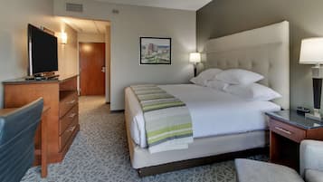 A hotel room with a bed, a desk, a chair, a television, and a picture on the wall.