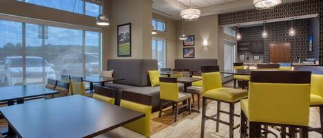 A modern restaurant with high ceilings, large windows, and a mix of seating options including tables and booths.
