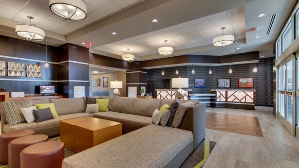 A modern lobby with a sectional sofa, ottomans, and a reception desk. - Drury Inn & Suites Columbus Polaris (Columbus)