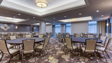 A spacious conference room with multiple tables and chairs, a patterned carpet, and a modern ceiling design.