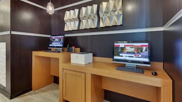 A reception desk with two monitors, a printer, and a wooden cabinet.
