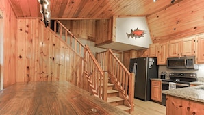 A wooden interior with a kitchen, a dining area, and a staircase. - Cartecay Canoe House | Ellijay, GA (Ellijay)