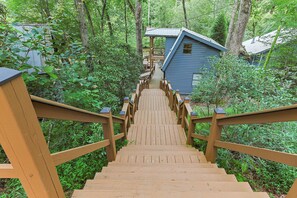 Una escalera de madera que lleva a una cabaña rodeada de un bosque denso.