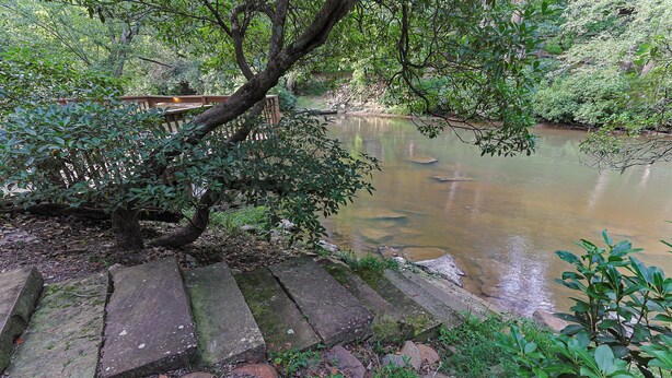 A stone pathway leading to a calm river with dense foliage on either side. - Cartecay Canoe House | Ellijay, GA (Ellijay)