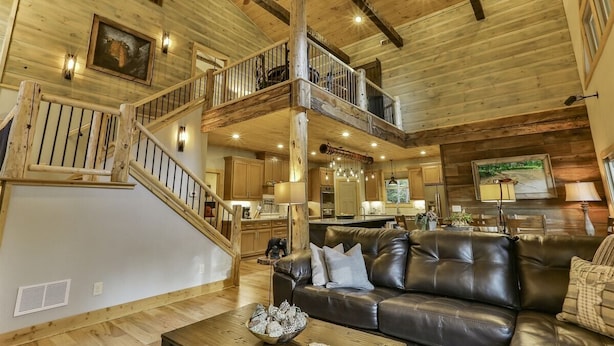Un interior espacioso con una escalera de madera, un sofá de cuero y una zona de cocina.