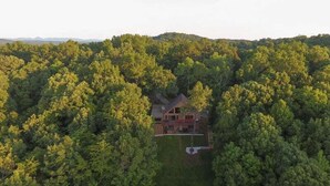 A house surrounded by dense forest, with a visible front yard and a two-story structure. - Mountain Lake Escape | Ellijay, GA (Ellijay)