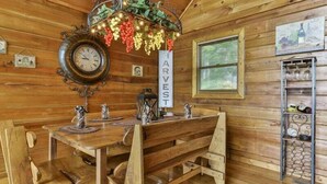 A wooden dining area with a vintage clock, a sign reading 'HARVEST,' and a metal shelf with glassware. - Mountain Lake Escape | Ellijay, GA (Ellijay)