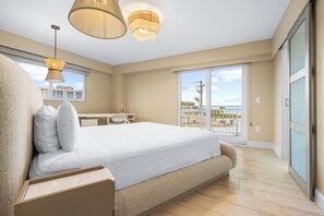 A bedroom with a large bed, a desk, and a balcony with a view. - Beachfront 2BR condo w/ private beach access & views (Siesta Key)