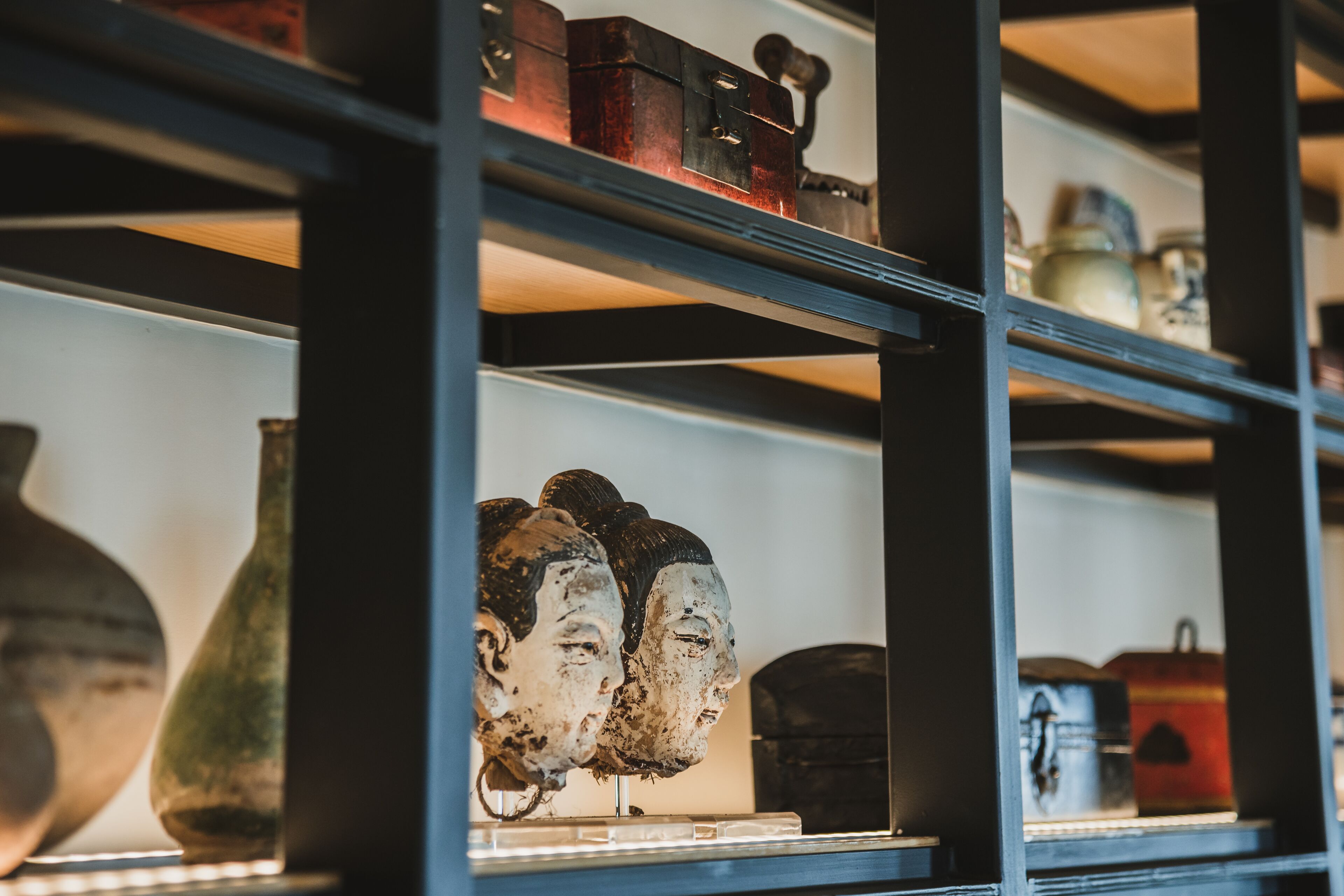 A display of antique items on shelves, including vases and boxes.