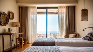 A hotel room with two beds, a desk with a lamp, a chair, and a view of the sea through large windows. - Sensi Azores Nature and SPA (Ponta Delgada)