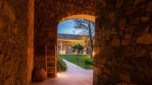 A stone archway leading to a courtyard with a paved path, a ladder, and a large pot. - Sensi Azores Nature and SPA (Ponta Delgada)
