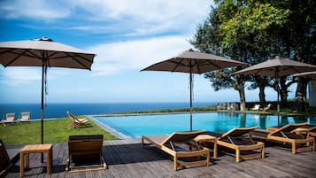 Una piscina techada, una piscina al aire libre, sombrillas