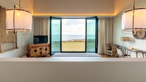 A bedroom with a large window, a wooden dresser, a television, and a wicker chair. - Sensi Azores Nature and SPA (Ponta Delgada)