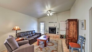 Una sala de estar con sofá, sillón, mesa de centro, chimenea y mueble de madera.