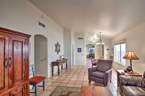A spacious living room with a wooden cabinet, a patterned rug, a leather sofa, and a dining area in the background.
