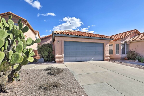 A residential house with a garage, a cactus in the foreground, and a clear blue sky.