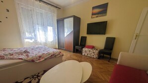 Een slaapkamer met een bed, een bureau, twee stoelen, een bank, een garderobe en een schilderij aan de muur.