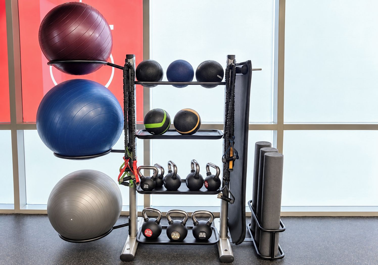 A gym with exercise equipment including kettlebells, medicine balls, and a pull-up bar.
