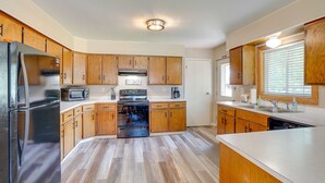 A modern kitchen with wooden cabinets, stainless steel appliances, and a central island. - Roosevelt Suite of Dakota Place Lodge in Medora! (Medora)