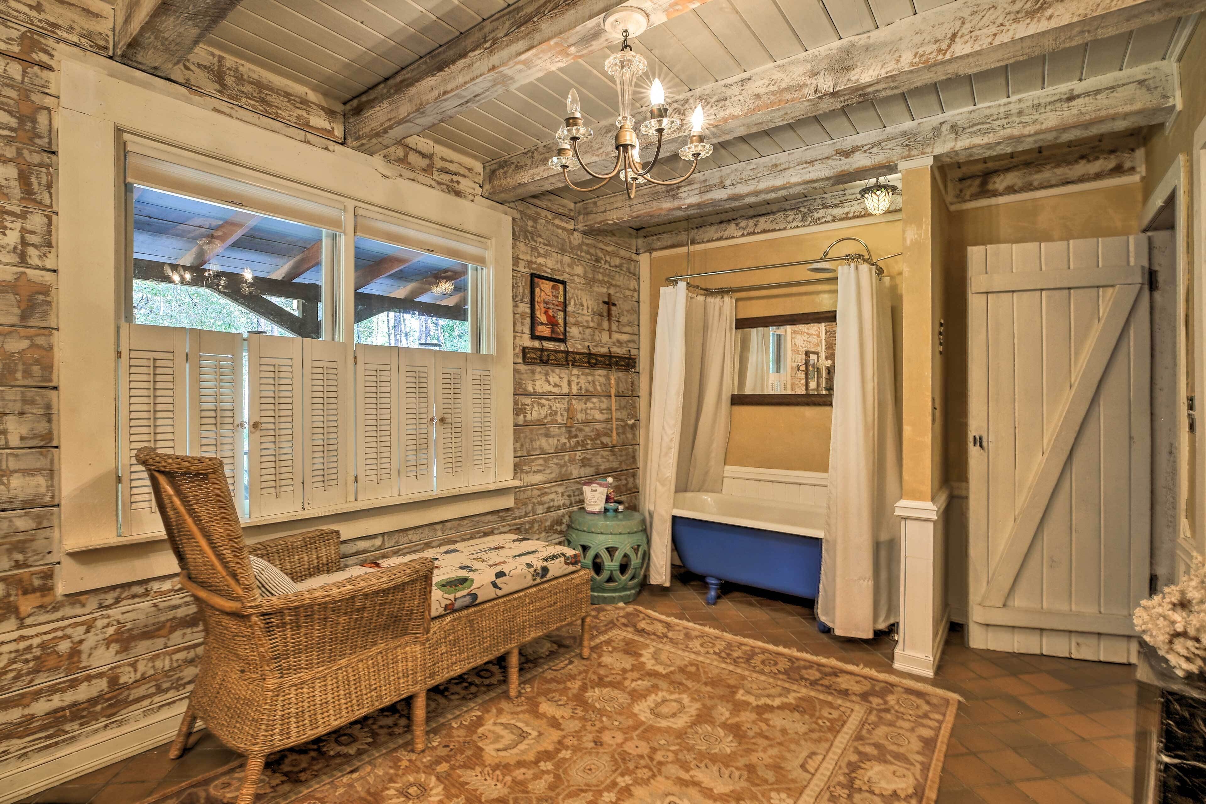 Une salle de bain rustique avec une baignoire bleue, une chaise en osier et un plafond en bois.