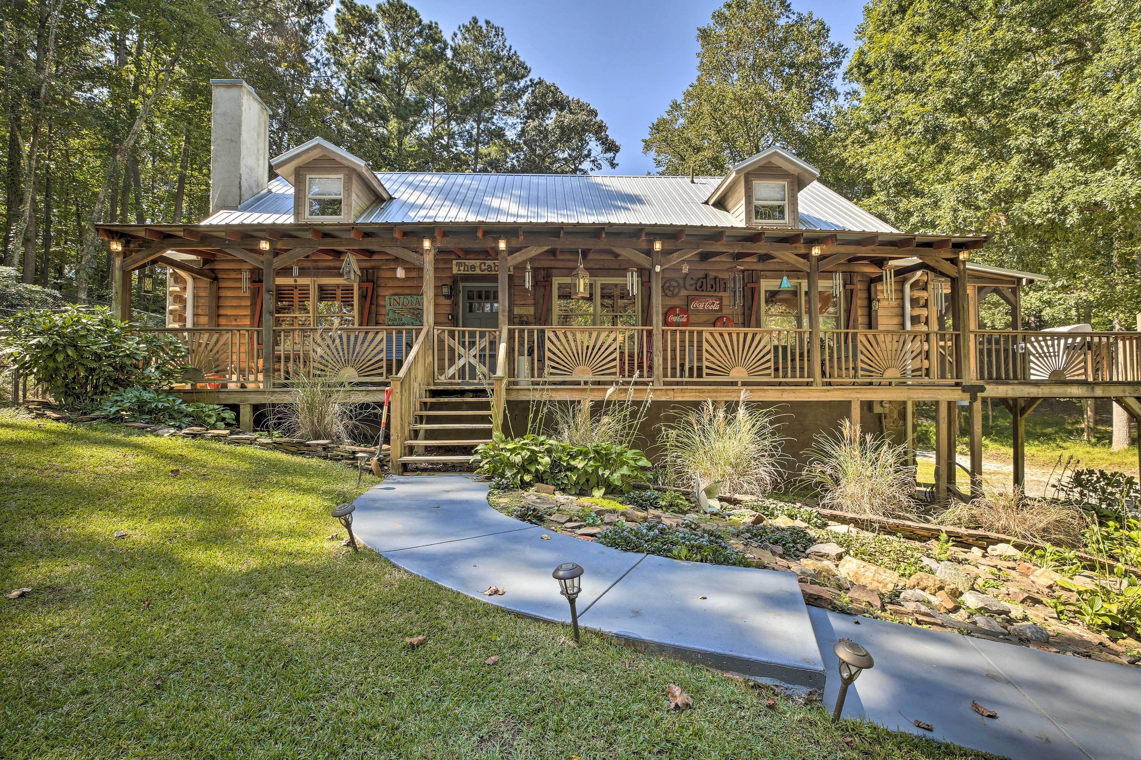 A rustic log cabin with a covered porch, a Coca-Cola sign, and a stone fireplace.
