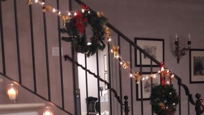 Un comedor con una escalera decorada con luces navideñas y guirnaldas.