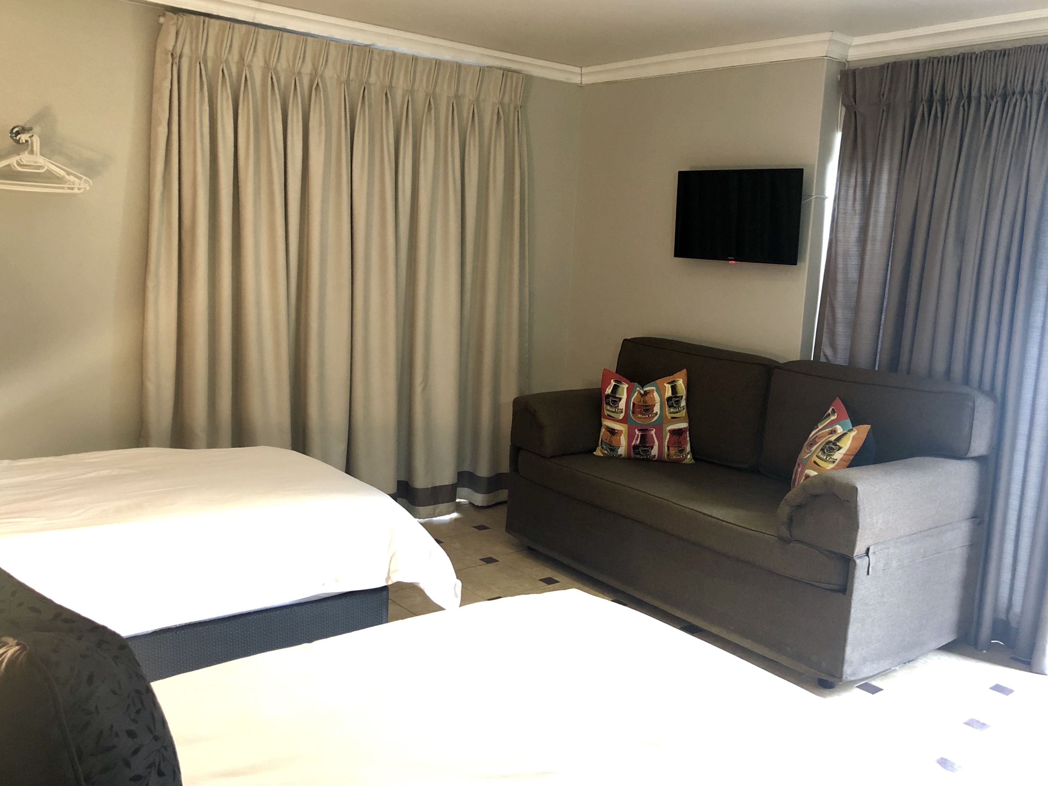 Una habitación de hotel con una cama, un sofá y un televisor montado en la pared.