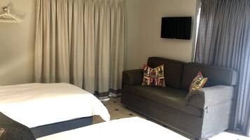 Una habitación de hotel con una cama, un sofá y un televisor montado en la pared.